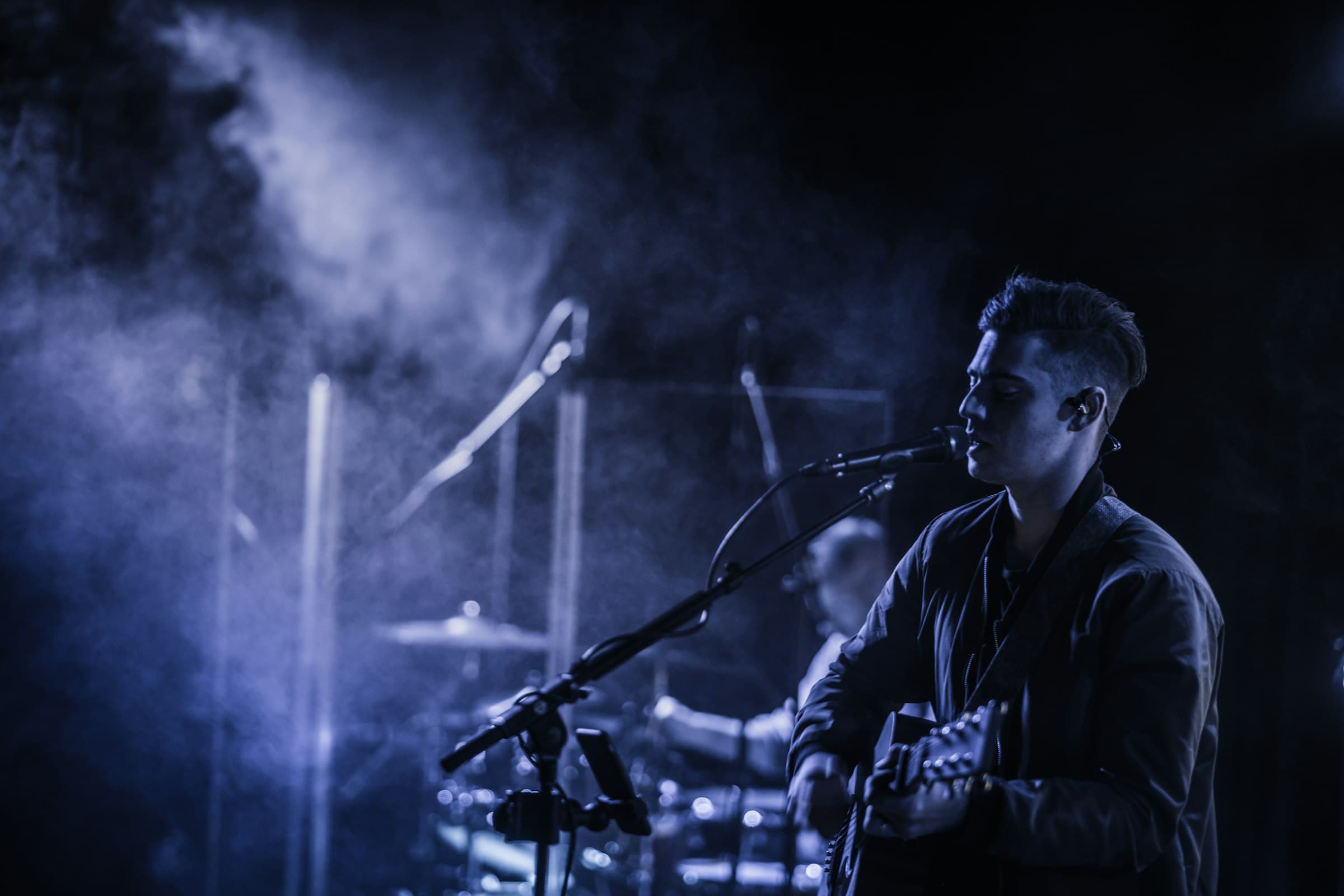 Guitarist singing into a microphone through stage haze