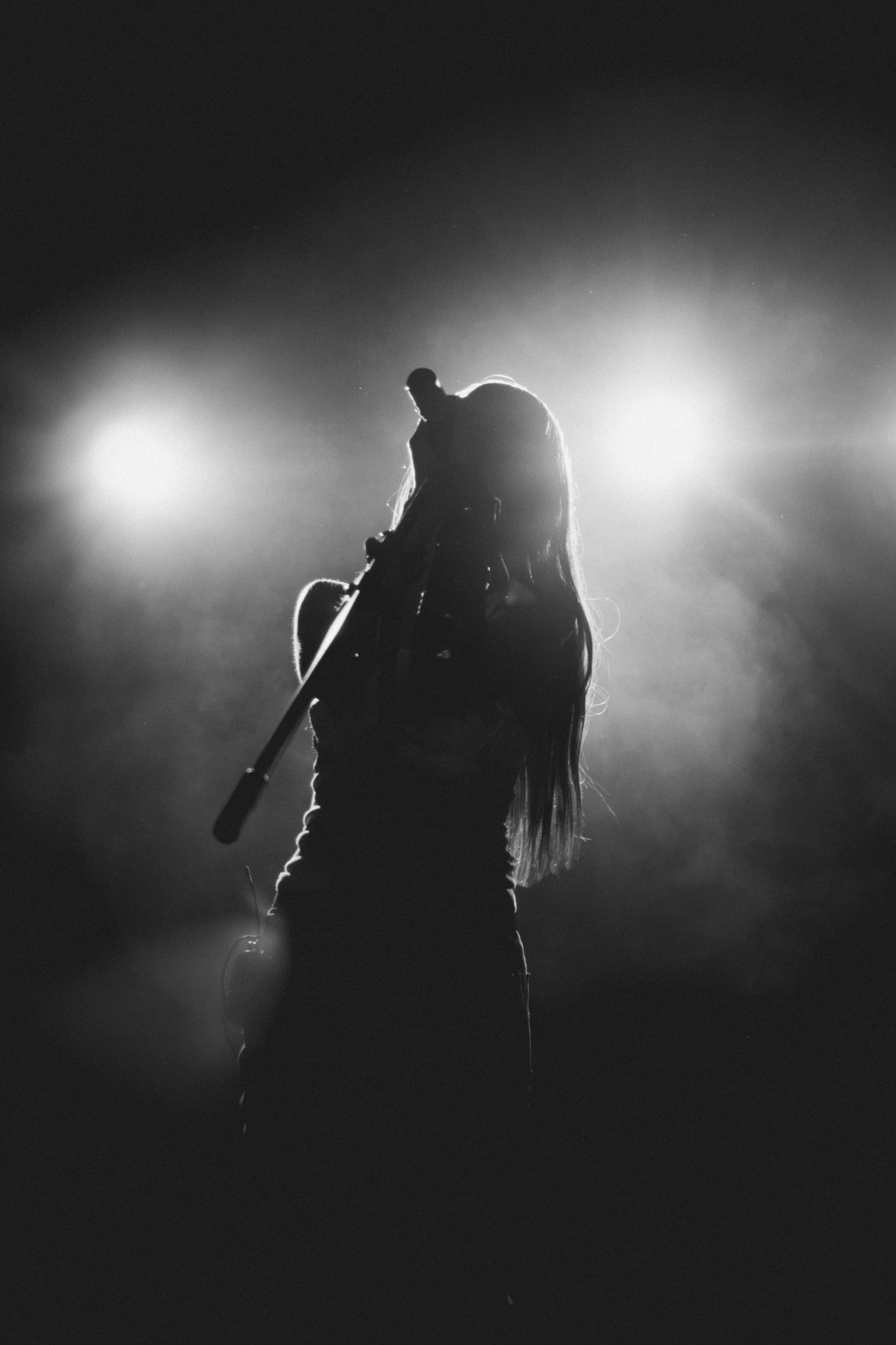 Singer in silhouette at a microphone, stage lights behind her